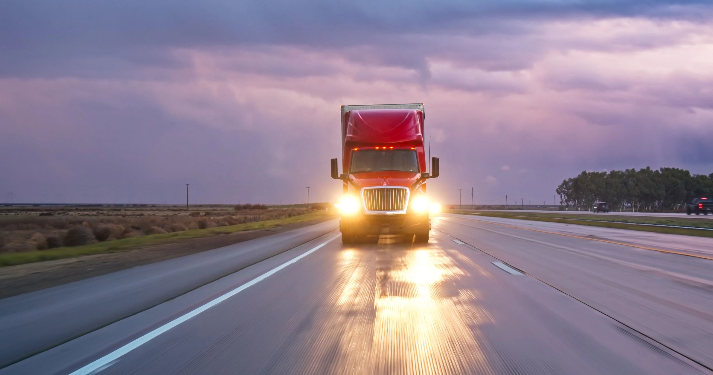 Highway scene under storm clouds with a truck in the distance